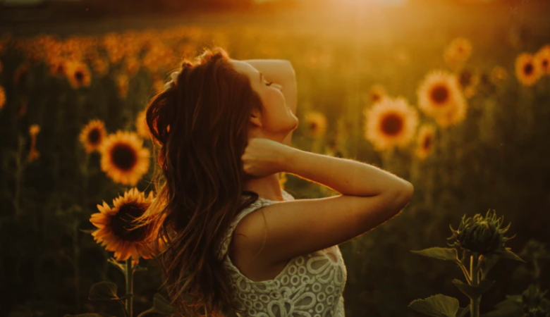 Happy woman in sunset sunflower field