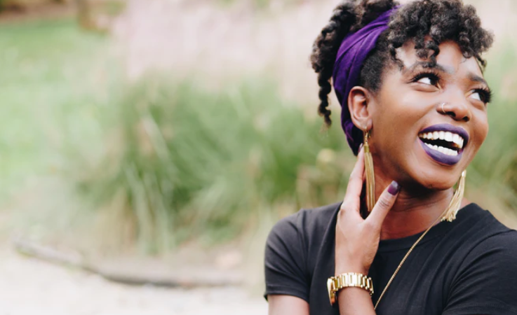 Woman wearing purple headband laughing in field