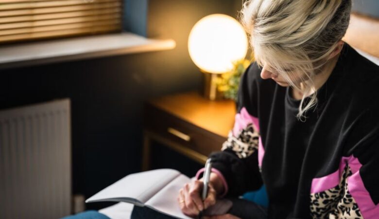 blonde haired woman writing about grief in bedroom