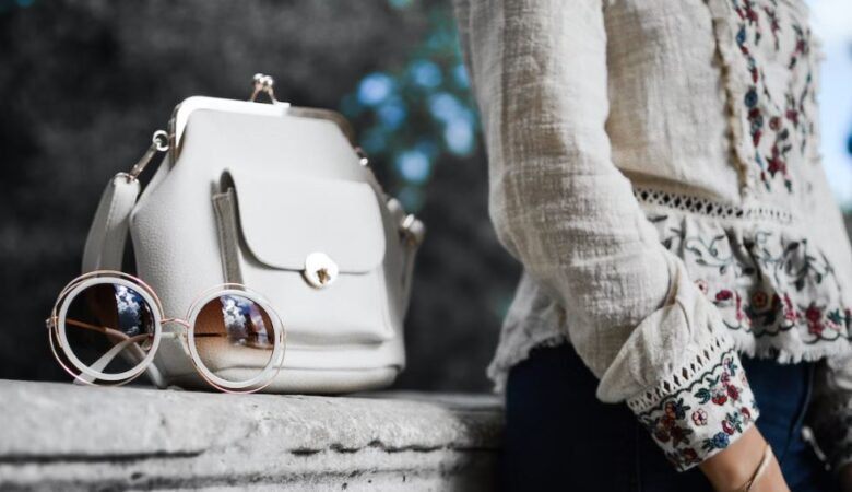 model woman leaning on side with handbag and sunglasses