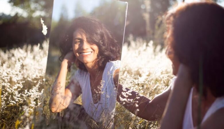 women in field smiling at herself in the mirror