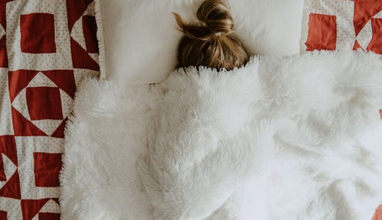 sick woman under fluffy duvet covers