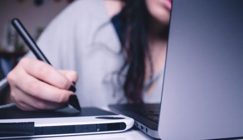 Woman worrying at work writing on her ipad hidden by laptop