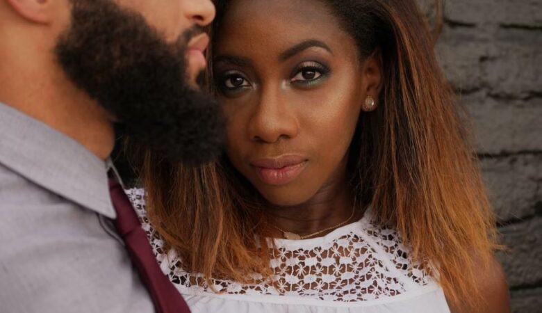 couple cuddling with woman staring at camera