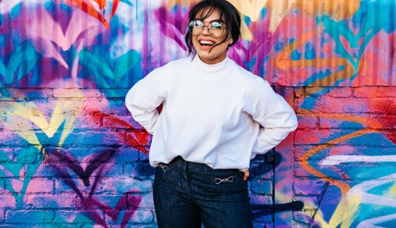 Happy single woman stood in front of a graffiti wall