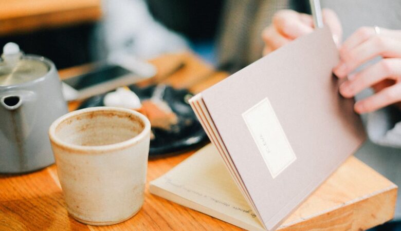 a woman in coffee shop writing in her journal