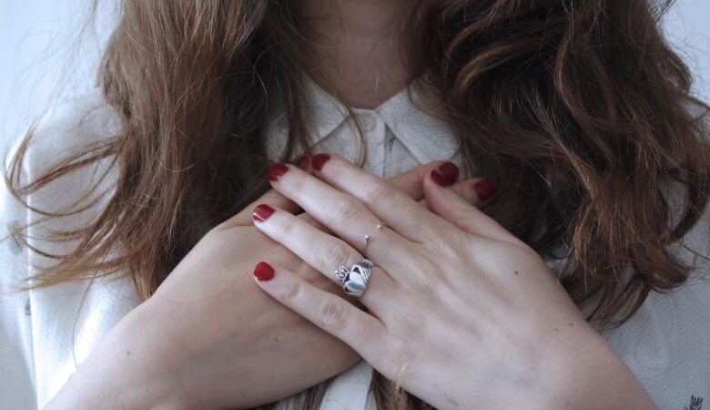 woman holding hands to her heart, with a heart shaped ring on finger