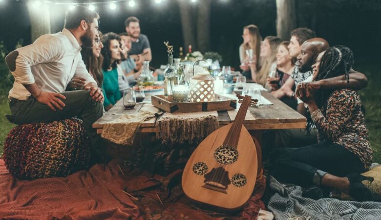 group of single and coupled friends having a conversation outdoors around a large table