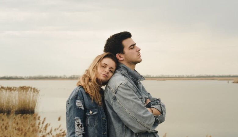 A woman leaning on a man in front of the beach, signifying a situationship