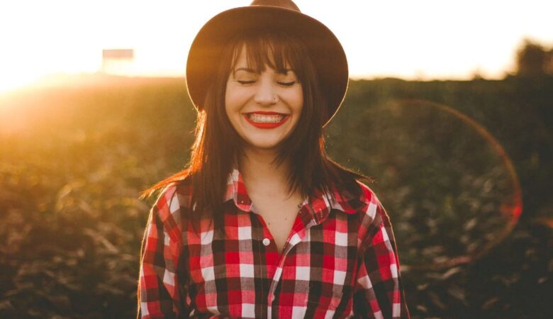 Smiling woman wearing hat in corn field