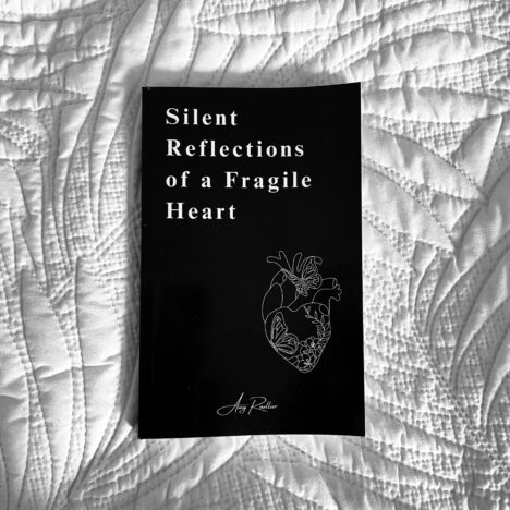 Picture of Amy Roullier's debut poetry book; Silent Reflections of a Fragile Heart, laying on a white duvet